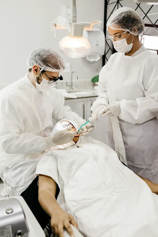 Dentista e assistente atendendo um paciente